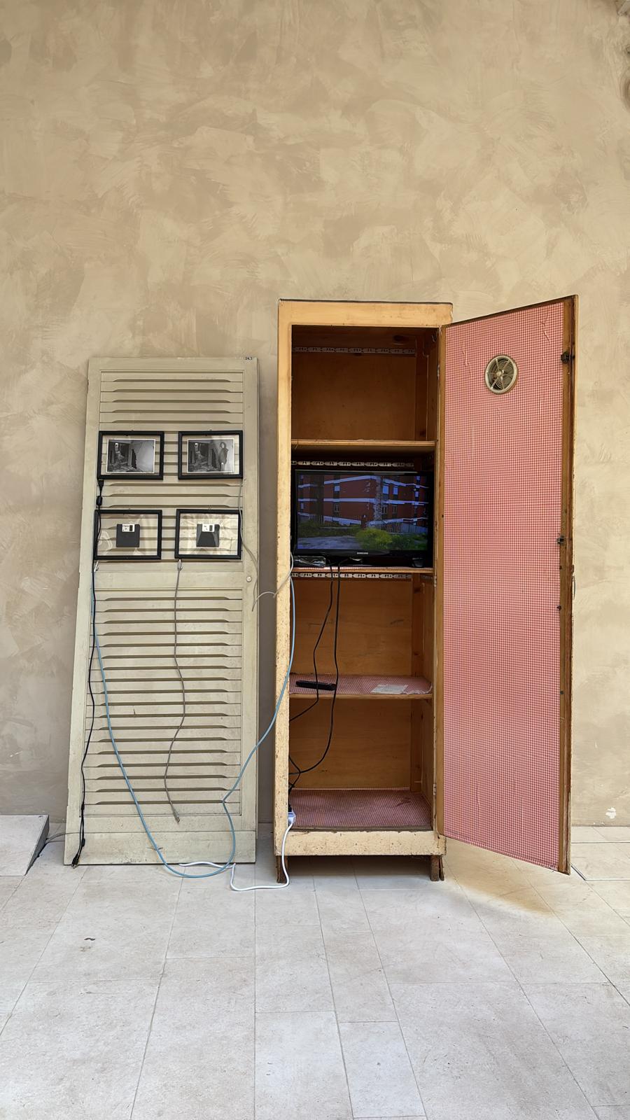 Armadio aperto con televisore e persiana con fotografie